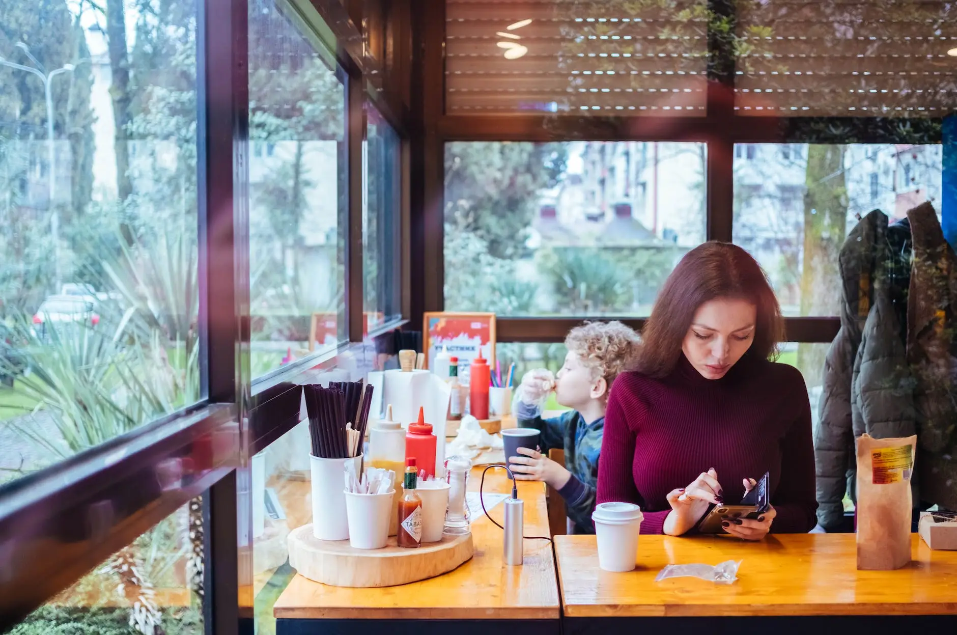 woman sitting beside table while using phone