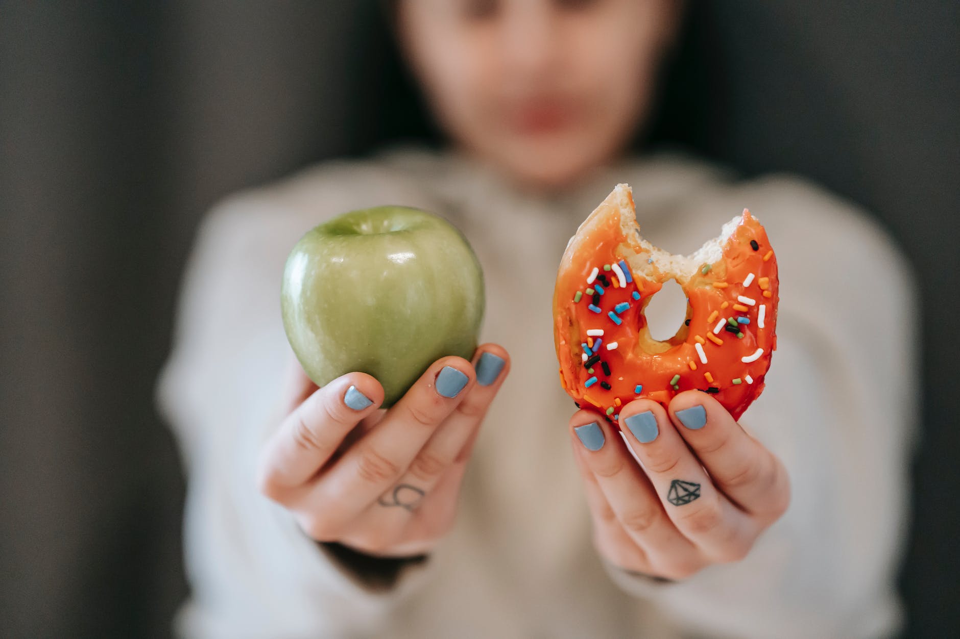 woman showing apple and bitten doughnutpexels-photo-6551415